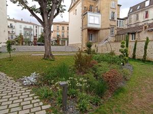 a garden in a park with a tree and buildings at Parenthèse Bergeracoise in Bergerac