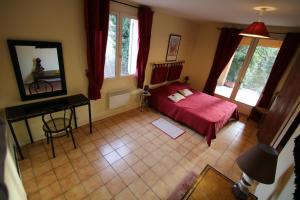 a bedroom with a red bed and a mirror at La Roseraie gîte 3 épis avec piscine in Ruoms