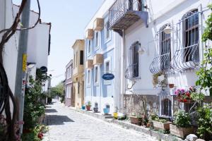eine Gasse mit weißen Gebäuden und Topfpflanzen in der Unterkunft Mauna Hotel in Bozcaada