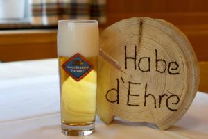 a glass of beer next to a wooden sign with the words hate crime at Gasthof Geier in Wörth an der Donau