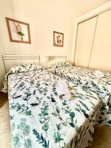 a bedroom with two beds with a floral bedspread at Feel The Vibe Alcaidesa in La Alcaidesa