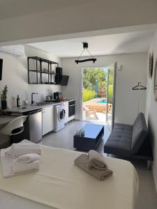 a white kitchen and living room with a bed and a table at Minimal Cream Apartment Pool-front in Paros in Parikia