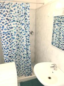 a bathroom with a sink and a shower curtain at Appartamento Sbirciamare by Zoom In Earth in Marina di Cecina +8 photos