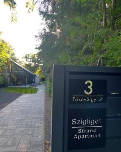 a sign in a park next to a walkway at Szigligeti Strand Apartman in Szigliget +8 photos