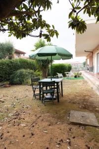 a picnic table with a green umbrella and two chairs at Vivilo Collection - Santa Laura Loft with Garden in Sperlonga