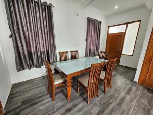a dining room with a glass table and chairs at HABITAT Holiday Home in Dharmsala