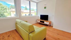 a living room with a yellow chair and a television at PARCHEGGIO GRATUITO ZONA OSPEDALE panoramico, tranquillo, nel verde in Trento
