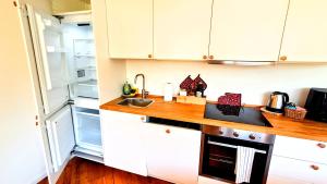 a kitchen with white cabinets and a sink and an open refrigerator at -Parcheggio Privato-Riscaldamento Pavimento-WiFi- zona OSPEDALE-CENTRO "COZY PANoRAMA" in Trento +43 photos