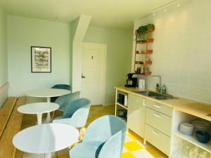 eine Küche mit zwei Tischen und Stühlen sowie einer Spüle in der Unterkunft Stub Inn Guesthouse in Stubbekøbing