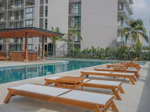 a row of wooden benches next to a swimming pool at Salinas del Mar Suite in Santa Marta