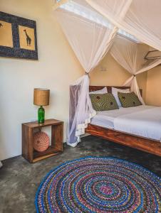 a bedroom with a bed and a table with a lamp at Muti Entebbe in Entebbe