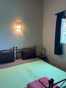 a bedroom with a bed with a light on the wall at Sidi Kaouki Beach Surfers Paradise in Sidi Kaouki