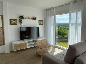 a living room with a tv and a large window at Casa da Marola in Zas