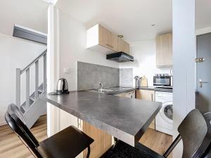 - une cuisine avec un comptoir et quelques chaises dans l'établissement La Capsule Colocation Appartement partagé à deux personnes maximum, à Rouen