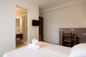 a bedroom with a white bed and a bathroom at Hotel Berna in Eraclea Mare