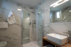a bathroom with a glass shower and a sink at Hotel Berna in Eraclea Mare