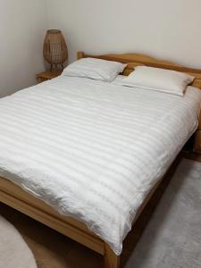 a bedroom with a bed with white sheets and a lamp at Friends Vlašić in Vlasic