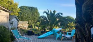a blue slide on a patio with chairs and a table at D'Ici ou D'ailleurs in Barneville-Carteret