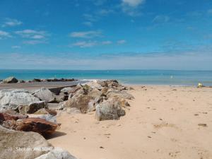 a beach with rocks on the sand and the ocean at D'Ici ou D'ailleurs in Barneville-Carteret