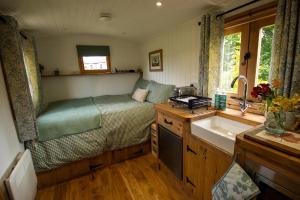 a small bedroom with a bed and a sink at Sycamore Shepherd's Hut in Hamsterley