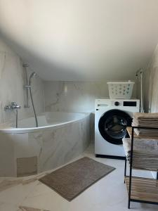 a bathroom with a tub and a washing machine at Ferienwohnung NAMALI in Schiefling am See +24 photos