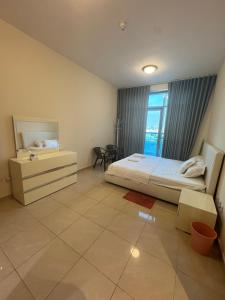 een slaapkamer met een bed, een ladekast en een raam bij Luxury Beachfront Apartment with Sea Views in Ajman  +8 foto's