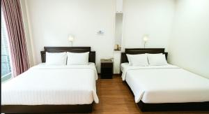 zwei Betten in einem Hotelzimmer mit weißen Laken in der Unterkunft Asia Mahanakhorn Travel in Bangkok