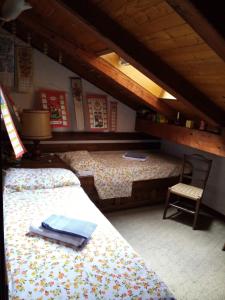 a attic room with two beds and a chair at Appartamento 19 Nigritella in Sappada +4 photos