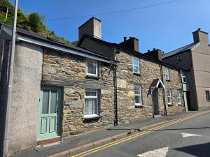ein altes Steingebäude mit grüner Tür an einer Straße in der Unterkunft Pet friendly two bedroom cosy cottage in Tanygrisiau