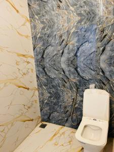 a bathroom with a toilet and a marble wall at The A-Frame house in Kūvattūr