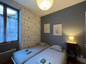 two twin beds in a room with a window at Appartement centre ville de Bourg d'Oisans in Le Bourg-dʼOisans