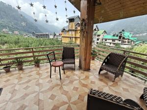 two chairs and a table on a balcony with a view at Apple Garden Cottage in Manāli