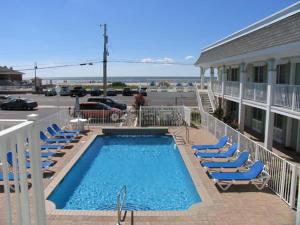 Una piscina con tumbonas al lado de un edificio. en Broadway Beach Unit 7, en Cape May