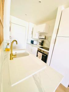 a white kitchen with a sink and a faucet at Studi0 coco0n, vue sur la marina in Marigot