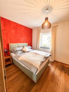 une chambre avec un lit et un mur rouge dans l'établissement Deluxe-Wohnung in Wasserburg Bahnhof - 94m2 - Smart TV - Terrasse - NEU, à Wasserburg am Inn