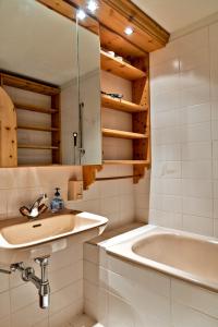 a bathroom with a sink and a bath tub at Chesa Grischuna 4pax - Madulain in Madulain +13 photos