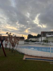 a white fence next to a blue swimming pool at Casa Temporada Itanhaém Portaria 24h in Itanhaém