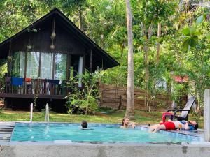 un gruppo di persone in una piscina con una casa di Nature World Jungle Paradise a Udawalawe