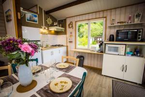 a kitchen with a table with a vase of flowers on it at Le Chalet Cavronnais in Cavron-Saint-Martin