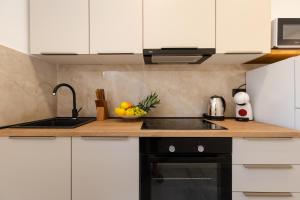 a kitchen with white cabinets and a sink and fruit on the counter at Alexis Residence in Mali Lošinj