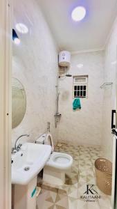 a bathroom with a white toilet and a sink at Kalitaani Homes in Fort Portal