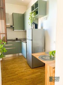 a kitchen with green cabinets and a stainless steel refrigerator at Verdincanto Relax e comfort a due passi dal centro in Lucca