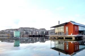 a red building on a dock in the water at Lägenhet i Skärhamn nära hav och natur! in Skärhamn
