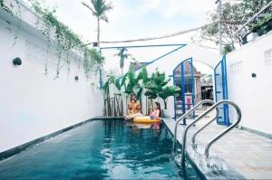 duas crianças a brincar numa piscina num edifício em Lazy Bear Villa By The Little Hoi An em Hoi An