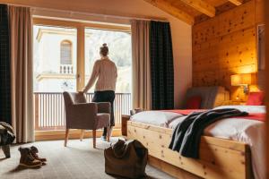 eine Person, die in einem Schlafzimmer steht und aus dem Fenster blickt in der Unterkunft Hotel Kirchenwirt in Kaunertal
