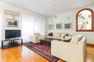 un soggiorno con mobili bianchi e una TV di Seafront Villa - with heated swimming pool a Trogir