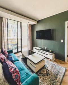 ケープタウンにあるAgape Apartment On park Centuryの青いソファと薄型テレビのあるリビングルーム