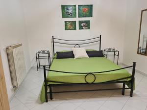 una camera con un letto verde con tre quadri sul muro di Casa Kikko a Mattinata