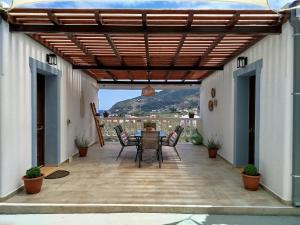 a patio with a table and chairs under a wooden pergola at Esperides Quiet Apartment Aigli With Amazing View in Skopelos Town