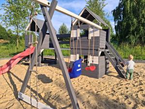 two children playing on a playground in the sand at Domki Dębowe Wzgórze in Potok Złoty